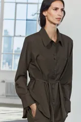 Camisa marrón de Zara Woman Collection, confeccionada en hilatura con viscosa. Tiene cuello solapa, manga larga con puño, bolsillo de plastrón en el pecho, cinturón ajustable con lazadas y bajo asimétrico. Se cierra con botones frontales.