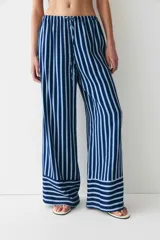 Pantalón de corte holgado en sarga con estampado a rayas verticales azules y blancas. Modelo de talle alto con cintura elástica y cordón de ajuste fino.