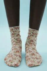 Calcetines finos semitransparentes color crema con estampado floral en tonos rosa y verde.