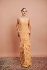 Vestido largo color durazno, entallado, con escote en V, breteles finos, drapeado en el frente y falda con volados.