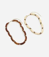 Collar de doble capa con diseño de tubitos curvos. Una de las cadenas presenta tubitos con acabado dorado brillante, mientras que la otra cuenta con tubitos de resina translúcida en tono ámbar, ambos intercalados con pequeñas cuentas metálicas. Posee un cierre de mosquetón y está confeccionado con materiales reciclados.