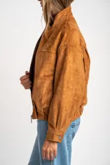Campera tipo bomber de cuero vegano color camel, con cierre frontal y cuello alto. Presenta un calce oversize y puños ajustados con botón.