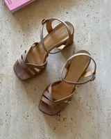 Sandalias color beige con plataforma y taco cuadrado, tiras cruzadas sobre el empeine y pulsera al tobillo con hebilla dorada. Fabricadas en cuero vacuno. Taco de 9cm.