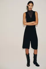 Body negro de tul con cuello alto y sisas amplias. Diseño drapeado en el frente y cierre inferior con broches a presión.