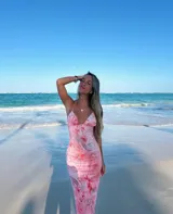 Vestido largo rosado con estampado abstracto en tonos rojos y grises, con breteles finos y espalda descubierta.