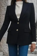 Blazer negra entallada con cuello solapa, manga larga con hombreras, bolsillos delanteros con solapa y cierre frontal con botones dorados.