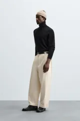 Pantalón negro de corte amplio, tipo balloon fit, con pinzas en la cintura, bolsillos laterales y traseros de ojal.