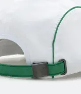Gorra blanca de cinco paneles con visera plana y ribetes verdes. Presenta un estampado con un pez koi, texto en japonés y la palabra "Tokyo" en verde.