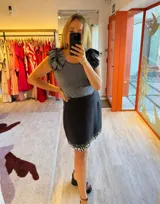 Falda blanca de lino y algodón, corte mini y bordado con lentejuelas plateadas en el ruedo.