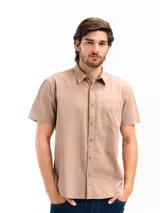 Camisa de manga corta color beige, confeccionada en 100% algodón, con cuello clásico, cierre frontal con botones y bolsillo en el pecho.