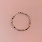 Pulsera trenzada en plata con detalles en oro, de diseño elegante y sobrio.