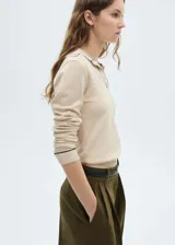 Jersey color beige de punto fino, con cuello polo con solapa y ribetes en contraste de color negro.