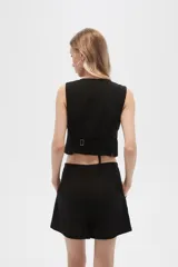 Chaleco negro sin mangas con cuello en V y cierre frontal con botones.