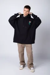 Buzo canguro negro de algodón friza, corte oversize y estampado de una rosa roja en el pecho.