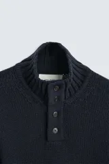 Jersey color crudo de corte recto, tejido en hilatura con mezcla de algodón y lana. Cuello subido con cierre frontal de botonadura y manga larga.