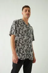 Camisa celeste con estampado de hojas, de corte slim, manga corta, cartera abotonada y logo bordado.