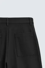 Pantalón negro de corte amplio, tipo balloon fit, con pinzas en la cintura, bolsillos laterales y traseros de ojal.