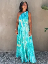 Vestido largo de tela fluida, color azul vibrante con estampado tie-dye en tonos beige/crudo. Diseño halter con tirantes finos ajustables y cintura marcada con lazo.