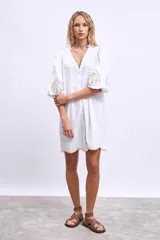 Vestido blanco de lino con escote en V, mangas cortas abullonadas y bordados florales en beige en mangas y ruedo.