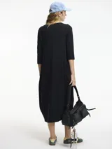 Vestido negro de manga 3/4 con cuello redondo y bolsillos laterales. Combina texturas de algodón y lino.