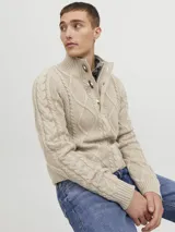 Sweater de punto color beige con cuello alto, cierre parcial con tres botones de madera y diseño con patrón de rombos y trenzas.