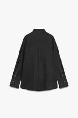 Camisa color durazno confeccionada en algodón, de corte amplio, con cuello solapa, manga larga con puños abotonados, hombros caídos, bolsillo de parche en el pecho, pinzas en la espalda y cierre frontal con botones.