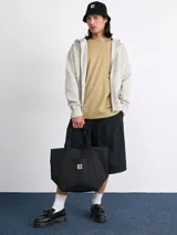 Bolso tote negro de lona de poliéster reciclado, con asas cortas y bolsillo frontal con etiqueta cuadrada tejida con el logo de Carhartt WIP.