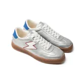 Zapatillas plateadas de cuero sintético con suela marrón, cordones blancos, talón azul y detalle de rayo blanco con borde rojo en el lateral.