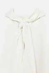 Top sin mangas color blanco, con cuello halter drapeado y bajo asimétrico con caída.