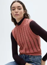 Chaleco de punto grueso color rosado, con diseño calado y cuello redondo.