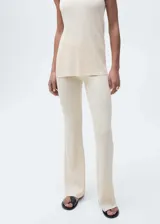 Pantalón largo de punto de canalé color crema, con cintura elástica, corte flare y tejido fino.