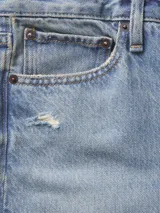 Pantalón jean celeste de tiro alto y corte relajado con roturas en ambas rodillas.