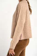 Sweater color beige de tejido de punto con cuello redondo y mangas largas con detalle de trenzas.