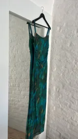 Vestido largo ajustado al cuerpo, confeccionado en microtul estampado con diseño abstracto en tonos verde, azul y marrón. Tiene breteles finos y forro interior opaco.