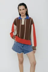 Sweater de punto con cuello polo, a rayas verticales color marrón y blanco, con mangas largas en bloques de color beige y rojo.