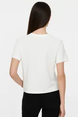 Remera blanca de algodón con estampado de flores azules y naranjas, de corte clásico y cuello redondo.