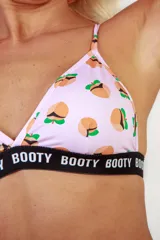 Corpiño deportivo rosa con estampado de duraznos y banda elástica con el texto 'BOOTY'.