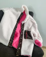 Campera corta de corderito color blanco con interior de polar y detalles en sherpa con estampado animal print.