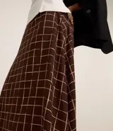 Pollera midi evasé con estampado de cuadros marrones y blancos, confeccionada en crepé.