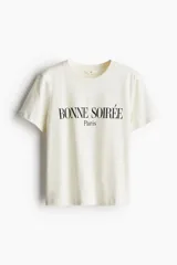 Remera blanca de algodón con cuello redondo y estampado con la frase 'Bonne Soirée Paris' en color negro.