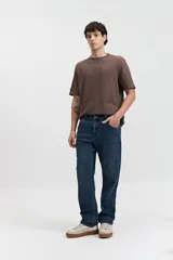 Pantalón de jean azul oscuro, corte recto, tiro medio, con bolsillos delanteros y traseros, y presillas para cinturón.