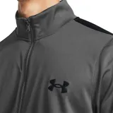 Conjunto deportivo Under Armour de hombre, color gris, compuesto por campera con cierre y pantalón largo. La campera tiene cuello alto, cierre frontal completo, bolsillos laterales y logo de la marca en el pecho. El pantalón tiene cintura elástica con cordón ajustable y logo de la marca en la pierna.
