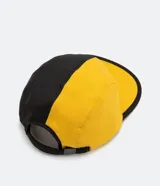 Gorra de cinco paneles bicolor, amarilla y negra, con visera plana y logo bordado en el panel frontal.