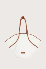 Bolso tipo tote de lona color blanco con ribetes y asas de cuero color marrón.