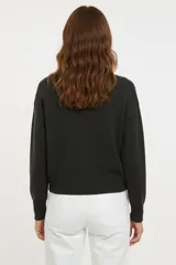 Cardigan de tejido de punto color crema, con cuello en V, manga larga y bolsillos frontales. Se abrocha con botones plateados.