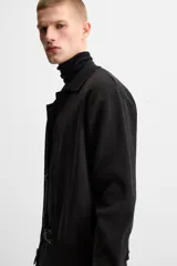Camisa de punto color negro, corte relaxed fit, con cuello solapa, manga larga y cierre frontal con botones.