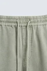 Pantalón color arena de corte recto, confeccionado en tejido de algodón y lino. Cuenta con cintura elástica ajustable con cordón, bolsillos delanteros y traseros de parche.