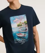 Remera azul marino de algodón, corte regular, cuello redondo y manga corta. Estampa rectangular con ilustración de barcos en la playa.