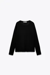 Jersey de punto color negro, con cuello redondo y manga larga de estilo raglán. Presenta acabados en rib en cuello, puños y bajo, con pequeñas aberturas laterales en el ruedo.