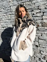 Buzo de polar color crudo con cuello alto y cierre de botones a presión. Parte superior con estampado animal print de cebra en tonos beige y negro.